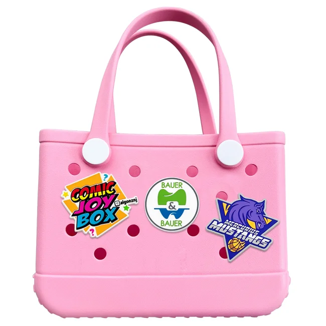 Assorted custom bag charms displayed on a rubber tote bag